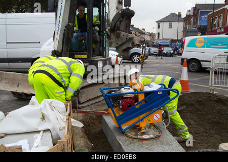 LONDON - OCTOBER 15TH: Unidentified workman using a sprobst vacuum stone magnet by Turnpike lane station on October 15th, 2014 i Stock Photo