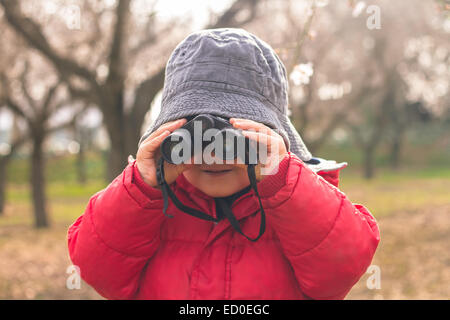 Portrait of a boy standing in a rural landscape looking through binoculars Stock Photo