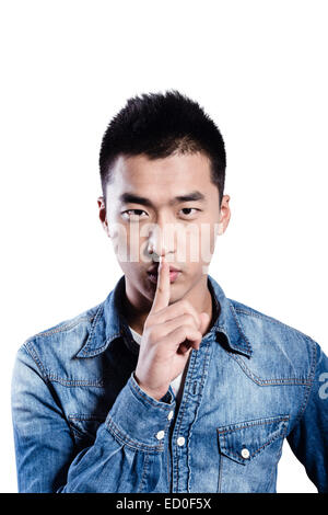 Portrait of young man with finger on lips Stock Photo