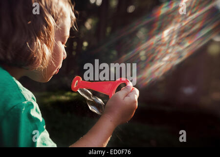 Girl (8-9) blowing bubbles Stock Photo