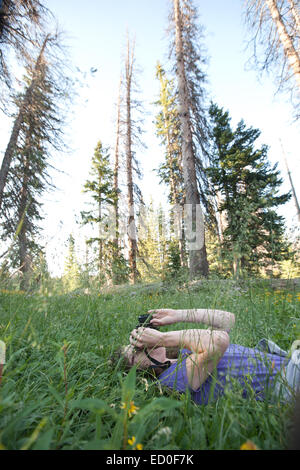 Woman photographing sky while lying in grass Stock Photo