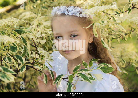 First communion girl (8-9) between leafs Stock Photo