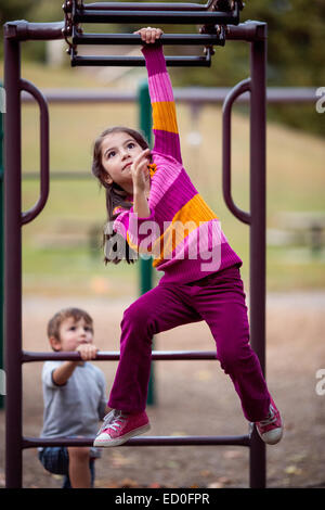 Girl and boy playing on climbing frame in a playground Stock Photo