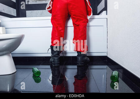 man in santa claus costume throwing up in the bathtub after the sylvester party Stock Photo