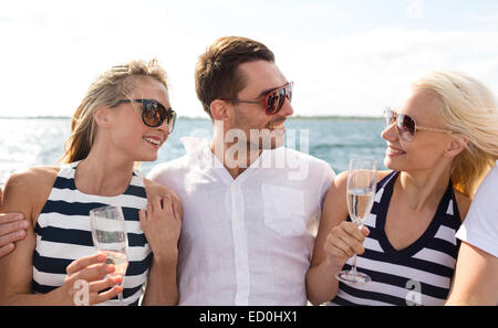smiling friends with glasses of champagne on yacht Stock Photo