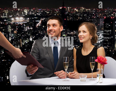 waiter giving menu to happy couple at restaurant Stock Photo