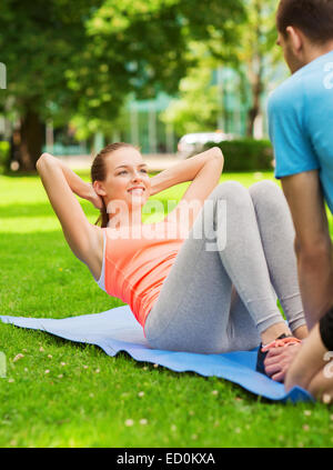 smiling woman doing exercises on mat outdoors Stock Photo