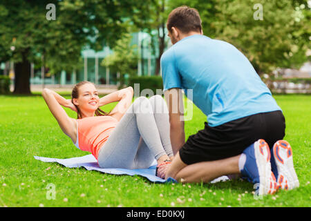 smiling woman doing exercises on mat outdoors Stock Photo