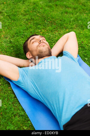 smiling man lying on mat outdoors Stock Photo