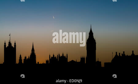 Silhouette of the Houses of Parliament and Big Ben at sunset with contrails of overflying planes in the sky Stock Photo