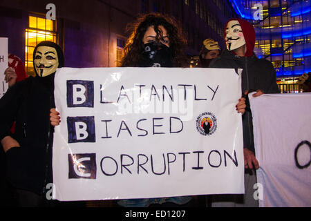 London, UK. 23rd Dec, 2014. Online activism group Anonymous march through London from the City to the BBC's HQ on Great Portland Street in protest against alleged biases and coverups of a 'paedophile ring'. PICTURED: A young woman poses with her placard for the 'Blatantly Biased Corruption' outside the BBC's Portland Place offices. Credit:  Paul Davey/Alamy Live News Stock Photo