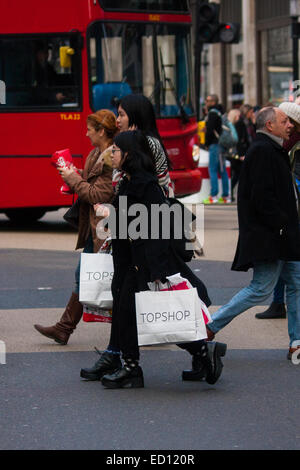 London, UK. 23rd Dec, 2014. Dubbed by retailers as the 'Golden Hour' thousands of shoppers use their lunch hour to do some last minute Christmas shopping in London's West End. PICTURED: Shoppers with their fistfuls of bags at Oxford Circus. Credit:  Paul Davey/Alamy Live News Stock Photo