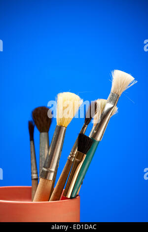 Paintbrushes in a can on a blue background