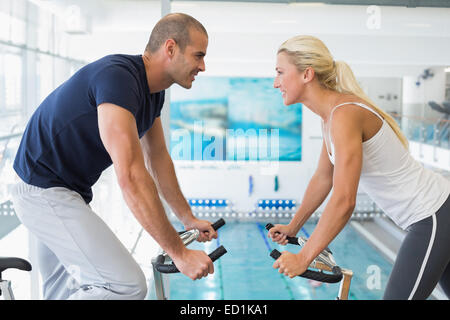 Side view of couple working on exercise bikes at gym Stock Photo