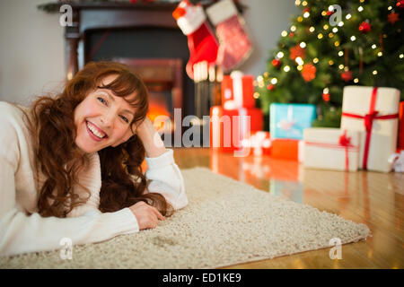 Smiling redhead woman lying on floor at christmas Stock Photo