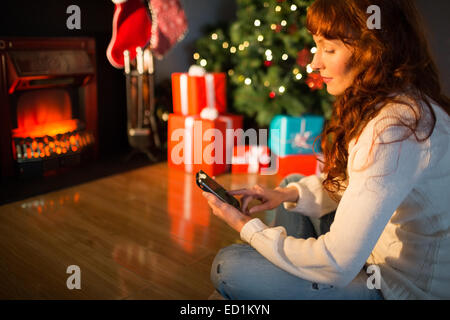 Smiling redhead using smartphone at christmas Stock Photo