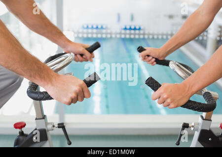Mid section of couple working on exercise bikes at gym Stock Photo