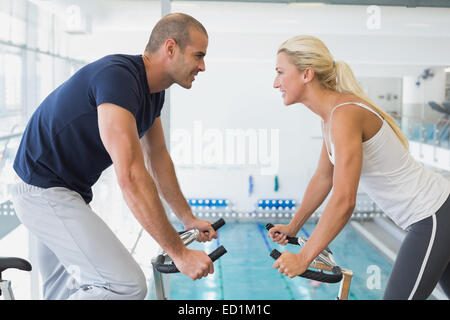 Side view of couple working on exercise bikes at gym Stock Photo