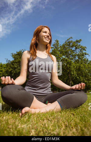 Portrait of a pretty redhead relaxing in lotus pose Stock Photo
