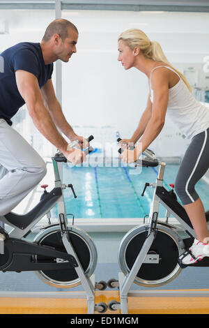 Side view of fit working on exercise bikes at gym Stock Photo