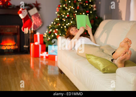 Relaxed redhead reading on the couch at christmas Stock Photo