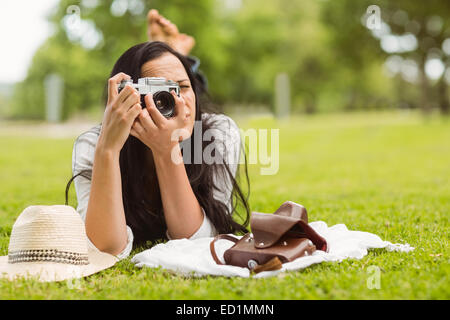 Brunette lying on grass taking picture Stock Photo