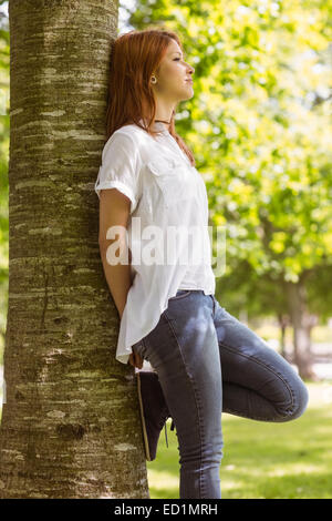 Portrait of a pretty redhead leaning against trunk Stock Photo