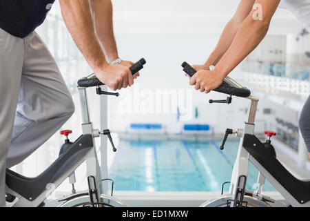Mid section of couple working on exercise bikes at gym Stock Photo