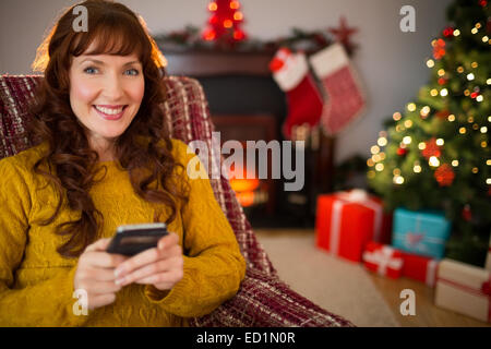 Happy redhead using mobile at christmas Stock Photo