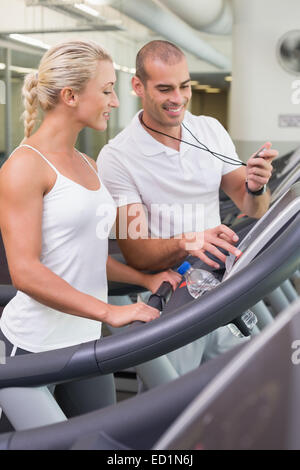 Male trainer timing his client on treadmill at gym Stock Photo