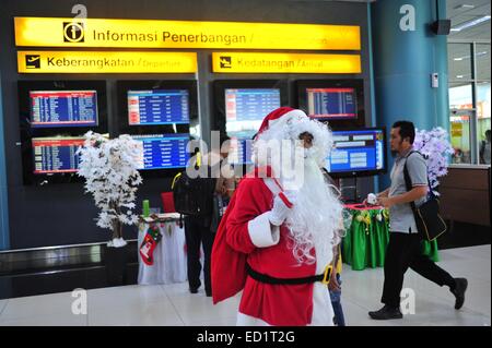 Jakarta, Indonesia. 24th Dec, 2014. A Santa Claus stands in front of a flight information screen at Terminal 3 of Soekarno-Hatta International Airport in Banten province, Indonesia, Dec. 24, 2014. Credit:  Zulkarnain/Xinhua/Alamy Live News Stock Photo