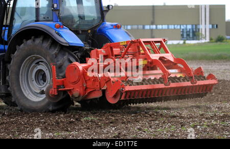 Rear closeup view of a articulated tractor with multiple plows that is plowing the earth Stock Photo