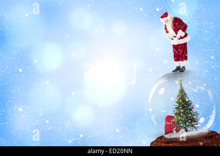 Composite image of santa standing on snow globe Stock Photo