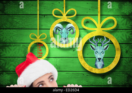 Composite image of pretty brunette in santa hat Stock Photo