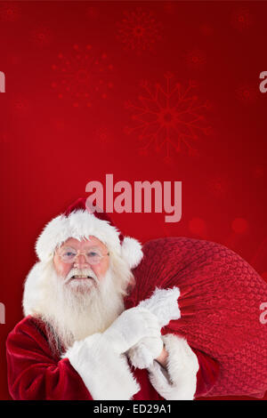 Composite image of jolly santa carries his sack Stock Photo