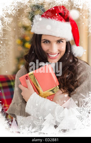 Composite image of festive brunette pressing gift at christmas Stock Photo