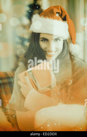 Composite image of festive brunette pressing gift at christmas Stock Photo