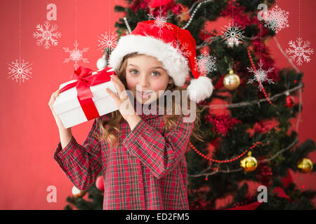 Composite image of festive little girl holding gift Stock Photo