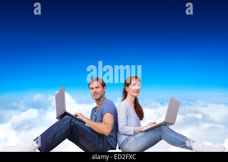 Composite image of couple both using laptops separately Stock Photo
