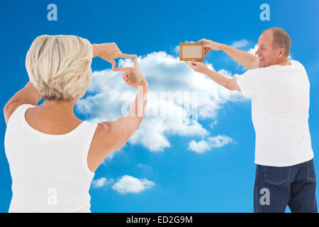 Composite image of mature couple hanging up picture frame Stock Photo
