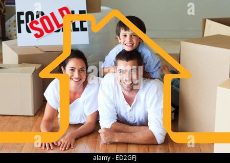 Composite image of family in their new house lying on floor with boxes Stock Photo