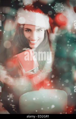 Composite image of festive brunette pressing gift at christmas Stock Photo