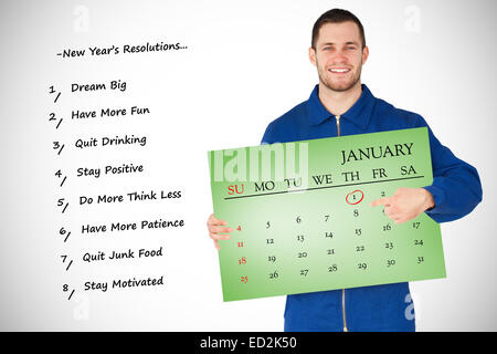 Composite image of smiling young mechanic in boiler suit pointing on calendar in his hands Stock Photo