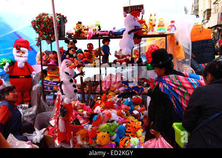 La Paz, Bolivia, 24th December 2014. An Aymara woman or cholita wearing traditional dress does her Christmas shopping at a street stall in a Christmas market. Credit:  James Brunker / Alamy Live News Stock Photo