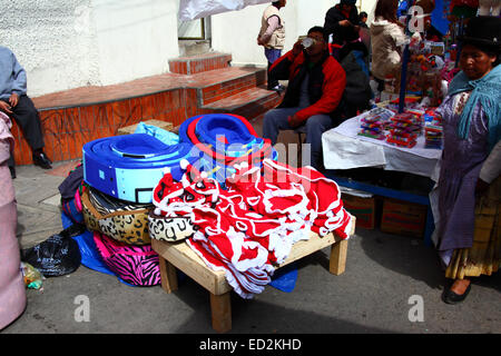 La Paz, Bolivia, 24th December 2014. An Aymara woman or cholita wearing traditional dress walks past a stall selling Santa Claus dog coats in a Christmas market. Credit:  James Brunker / Alamy Live News Stock Photo