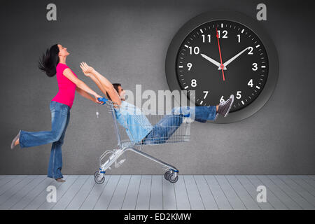 Composite image of young couple having fun with shopping cart Stock Photo