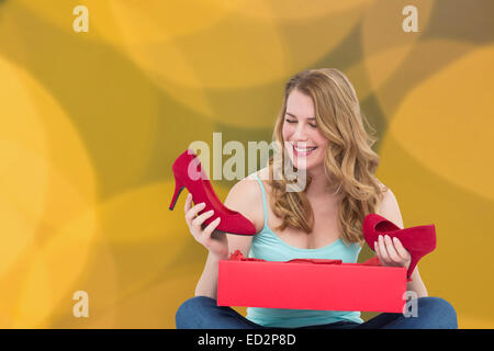 Composite image of blonde woman discovering shoes in a gift box Stock Photo