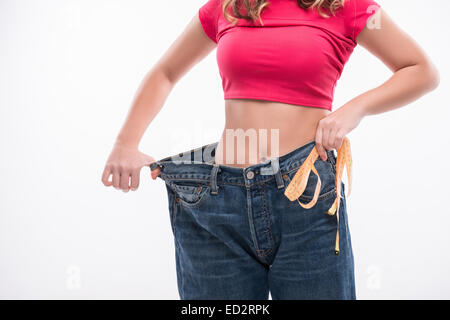 Slim waist of young woman in big jeans with measuring tape showi Stock Photo
