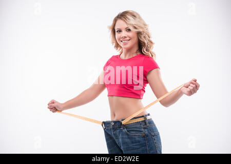 Slim waist of young woman in big jeans with measuring tape showi Stock Photo