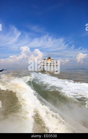 Boat wake and cargo ship to the sea Stock Photo